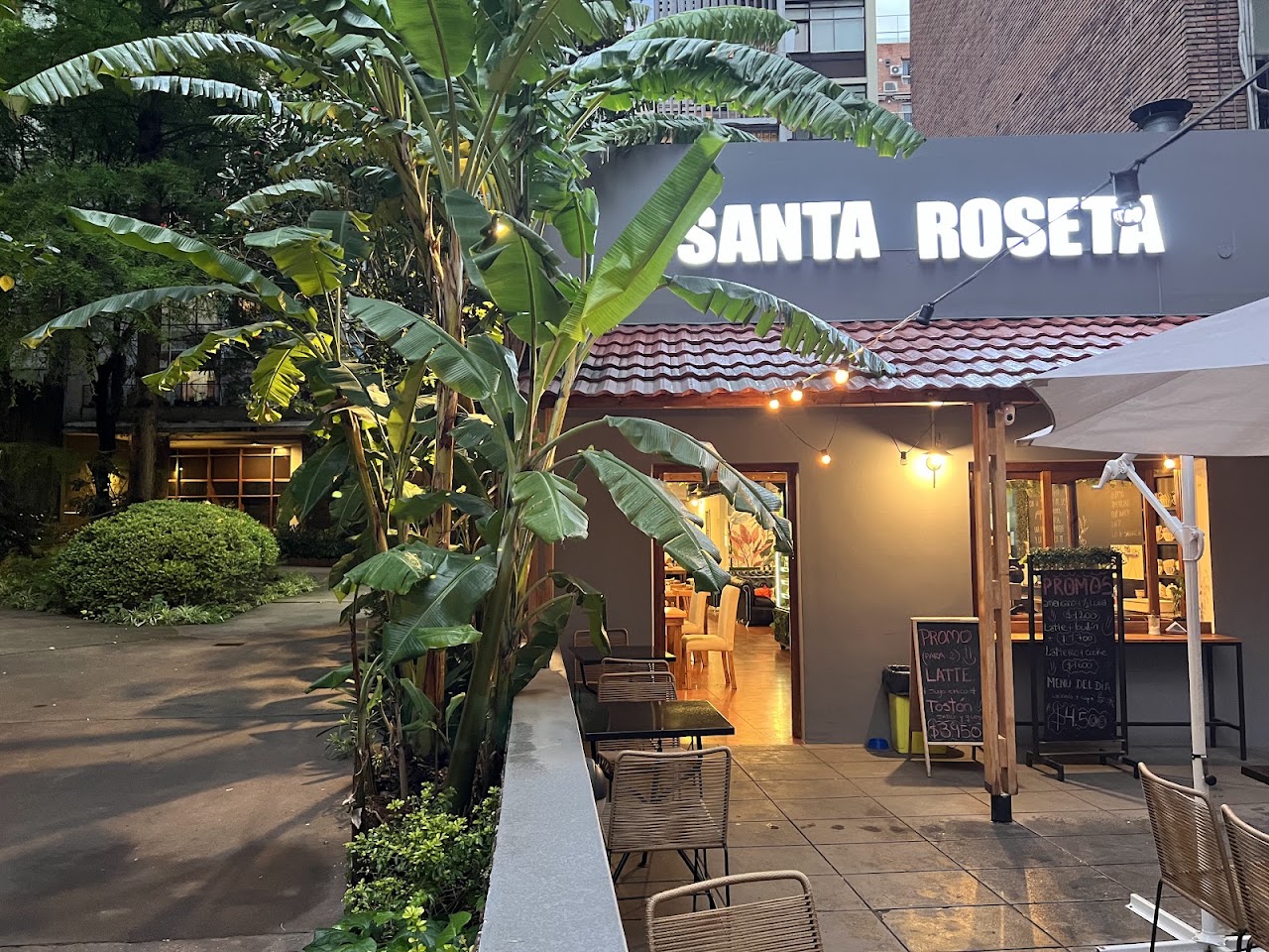 Fachada de Santa Roseta, cafetería en Belgrano, con cartel luminoso y patio con plantas