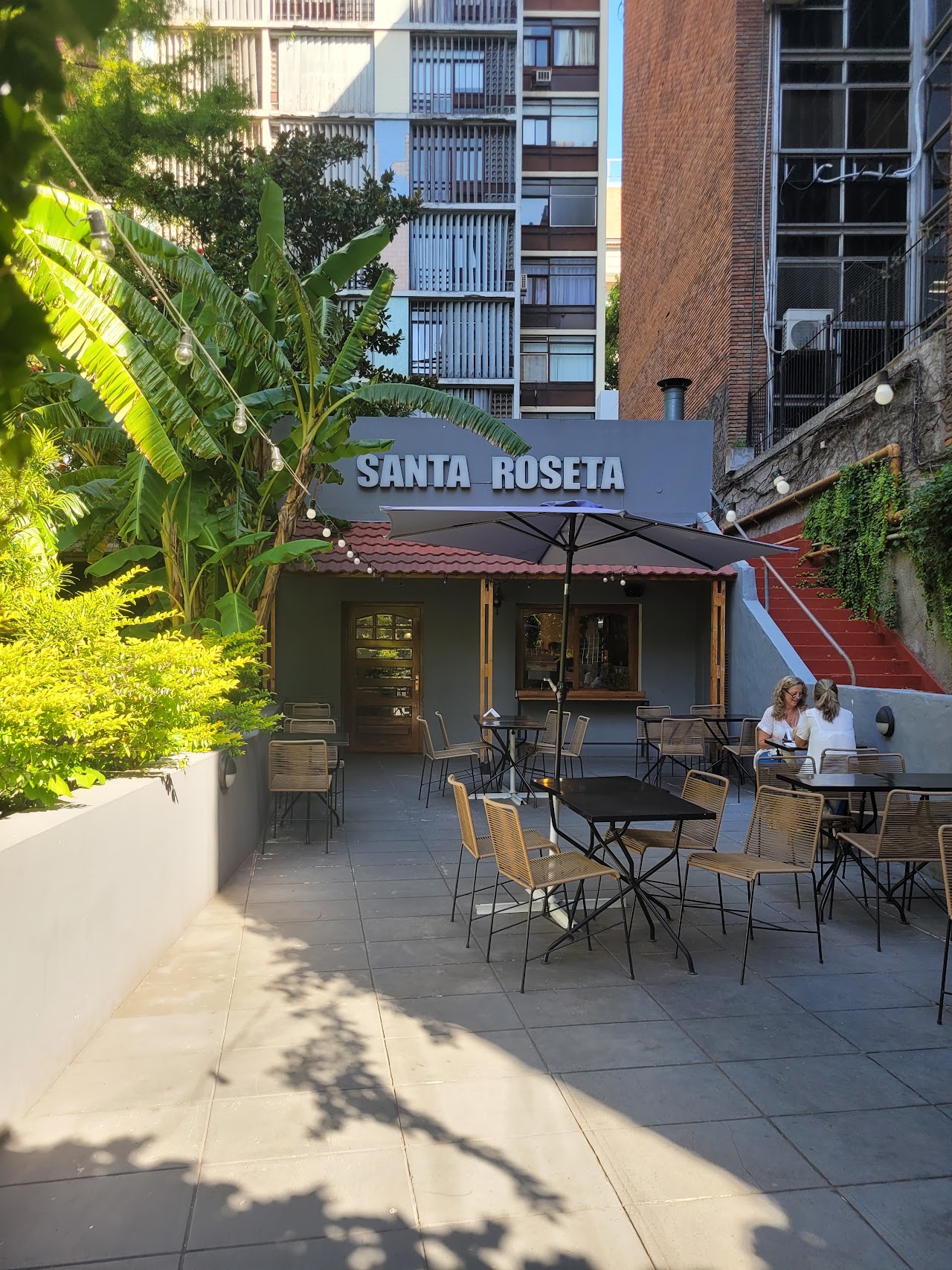 Patio exterior de Santa Roseta con mesas y plantas tropicales